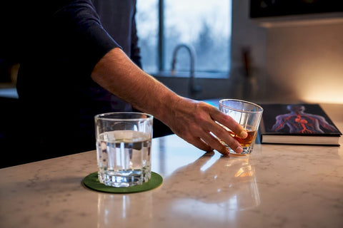 Man setting aside alcohol beside water glass